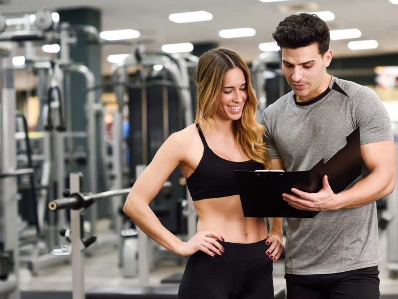 Personal trainer and client looking at her progress at the gym. Athletic man and woman wearing sportswear.